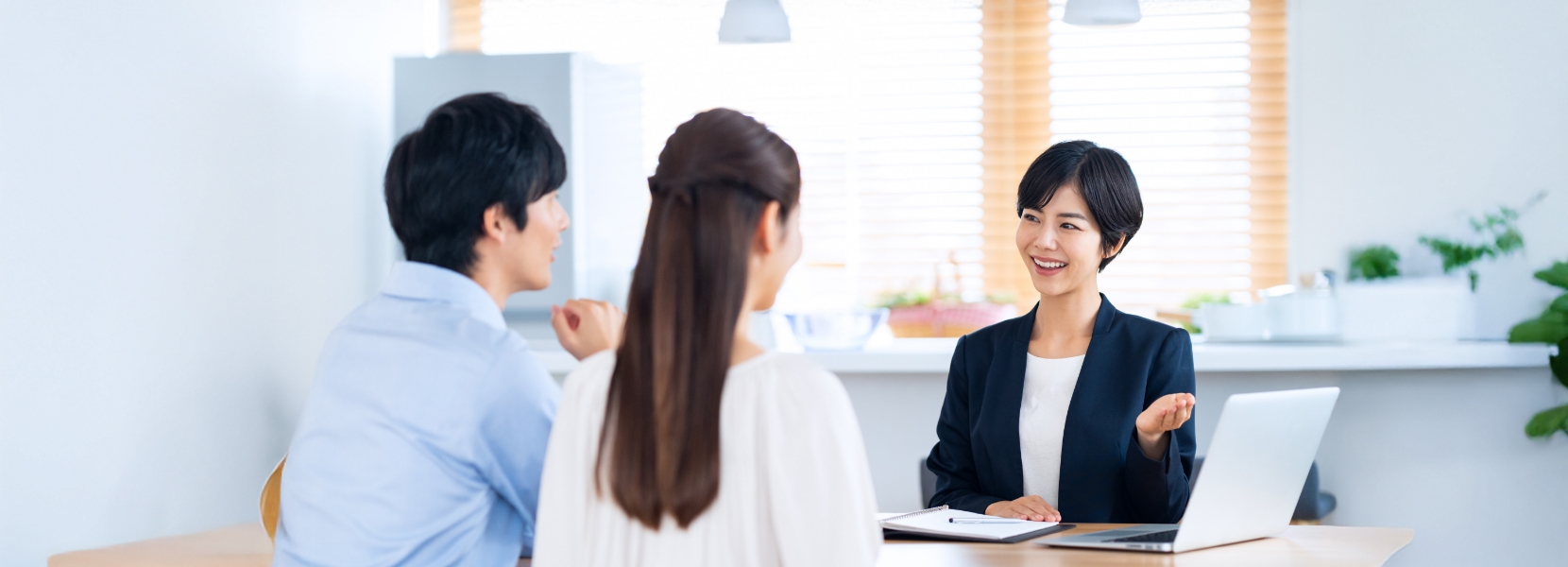 スーツを着た女性が男性と女性に説明している写真