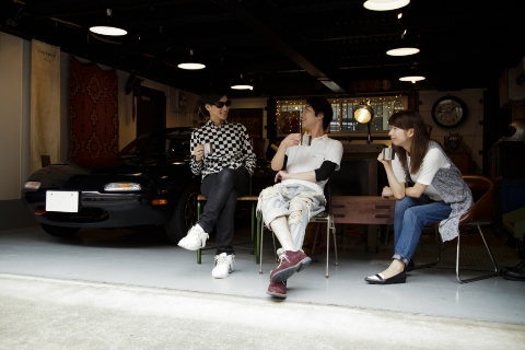 ガレージで話す男性2人と女性1人